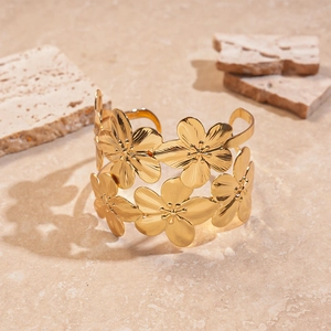Detailed close-up of golden wide open cuff bracelet with textured 3D floral petals