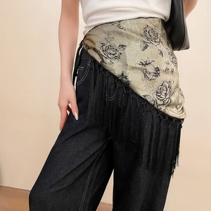 Close-up of golden silk waist scarf with black rose prints and decorative tassels