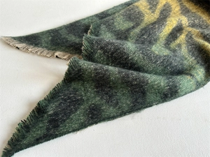 Gros plan sur une écharpe léopard avec motifs verts et noirs et détails de franges