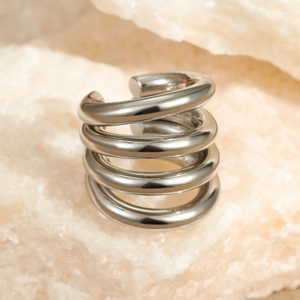 Polished silver four-layer spiral ear cuff on natural stone, minimalist stainless steel design
