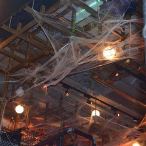 Creepy white spider web decor stretched across a wooden ceiling with warm lighting
