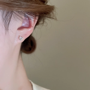 Close-up of a silver butterfly stud earring with mother-of-pearl wings on a person ear