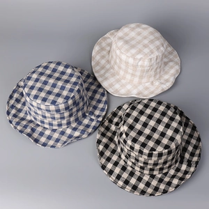 Flat lay of plaid linen bucket hats in navy blue beige and black colors with check patterns
