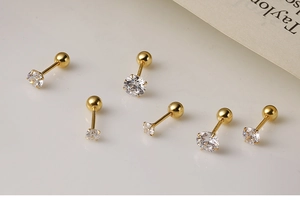 Detailed macro of gold four-prong earrings with clear cubic zirconia and screw backs