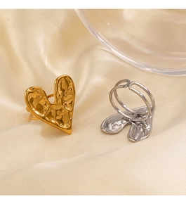 Detailed view of melting heart ring with irregular hammered texture on beige satin