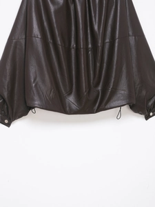 Dettaglio del bomber in pelle marrone scuro con coulisse sul fondo e bottone in metallo sui polsi