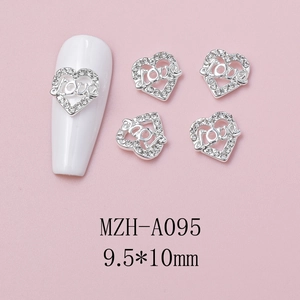 Macro view of silver heart-shaped nail charms with Love engraving and small rhinestones