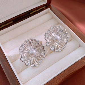 Makroaufnahme von Vintage-Blumenohrringen mit Perle in einer hölzernen Schmuckschatulle