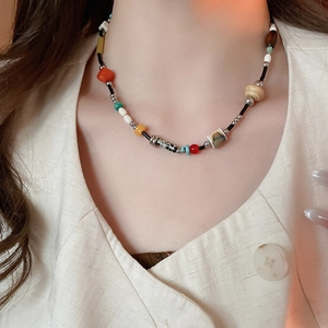 Close-up of bohemian beaded necklace with geometric stone resin and wood beads on model