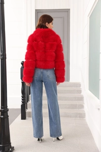 Rear view of a red faux fur coat paired with blue straight jeans and white high heels