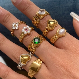 Close-up of assorted gold rings with emeralds and pearls worn on a denim background