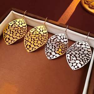 Detailed view of hollow leaf earrings in gold and silver finishes in a jewelry box