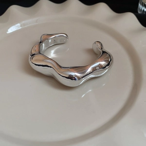 Vista dettagliata del bracciale argento irregolare con design a onde su vassoio