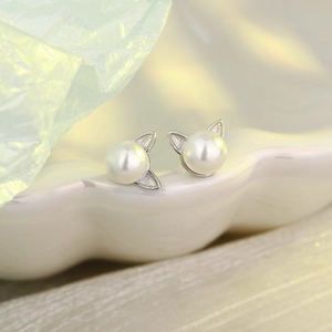 Minimalist silver cat ear pearl earrings displayed in a decorative white shell tray