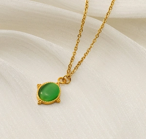 Vue détaillée du pendentif œil-de-chat vert sur une chaîne en acier inoxydable plaqué or 18K