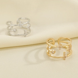 Detailed close-up of hollow gold and silver cross rings with sparkling zircons