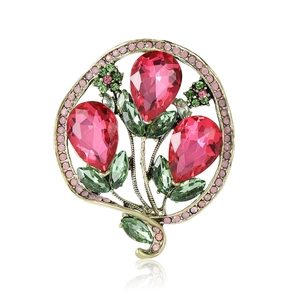 Golden flower brooch featuring pink teardrop gemstones and green crystal leaves