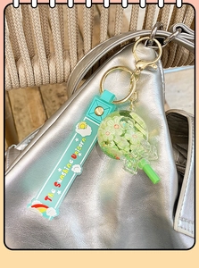 Mint green lollipop keychain with rainbow unicorn strap hanging on a silver bag