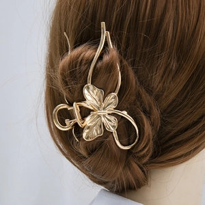 Golden metal hair claw clip with floral design shown on model with brown hair