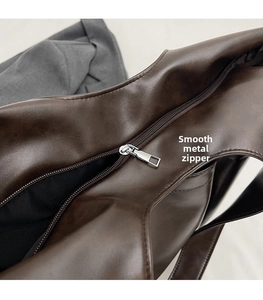 Detail of a smooth silver metal zipper on a dark brown leather tote bag closeup
