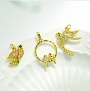Detailed macro view of 18K gold-plated bird pendants set with sparkling white zircon stones