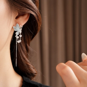 Gros plan d'un clou d'oreille papillon élégant avec pampille en cristal sur un modèle