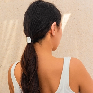 Detail of silver metallic geometric hair tie on a low ponytail with soft shadows