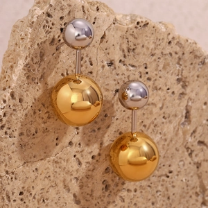 Detail von zweifarbigen Gold- und Silberkugel-Ohrringen auf strukturiertem Stein