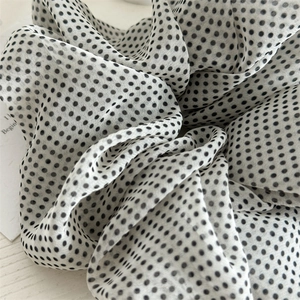 Close-up of white mesh scrunchie with black polka dots on a wooden background