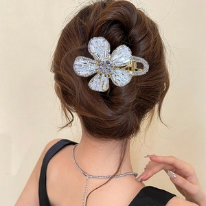 Elegant gold flower hair claw clip with sparkling zircons worn on a ponytail