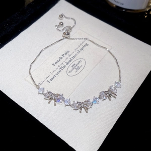Close-up of adjustable silver bow bracelet with zircon stones on premium jewelry card