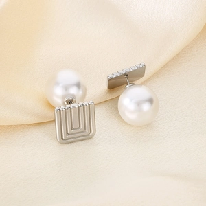 Detailed view of vintage square metal and pearl earrings on soft beige silk background