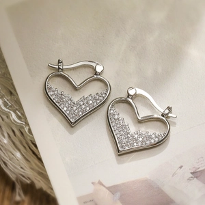 Elegant gold-plated heart hoop earrings with sparkling cubic zirconia on white magazine background