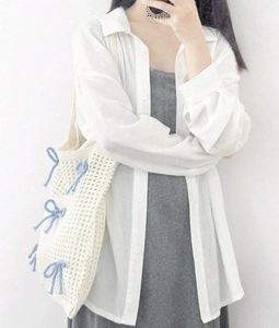 Detail of a beige knit tote bag with a light blue bow accent worn with casual outfit