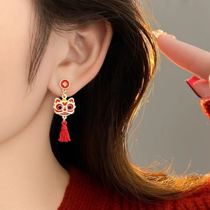 Boucles d'oreilles chinoises danse du lion avec pompons rouges portées par un mannequin