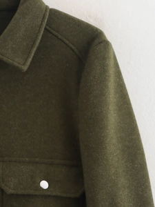 Détail de la veste en laine vert foncé montrant le col classique et la poche à bouton