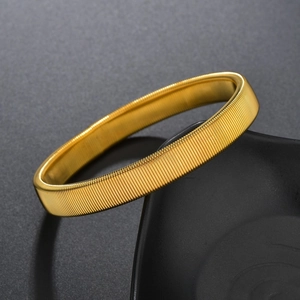 Detailed close-up of a gold punk metal spring elastic bracelet with wavy texture