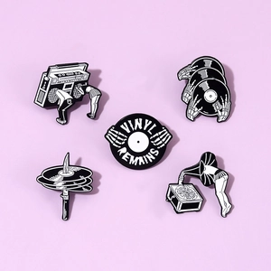 Macro shot of 5 black and white music enamel pins featuring vinyl records and skulls