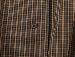Macro view of brown plaid cotton fabric with a dark brown four-hole button detail