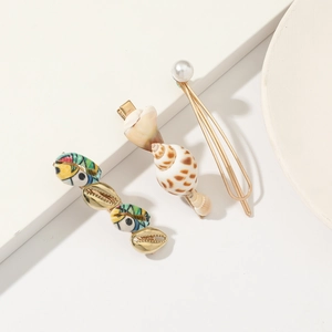 Detailed shot of three golden hair clips with natural shells, pearls and colorful prints