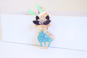 Macro detail of a golden cat keychain featuring sparkling blue rhinestones and bow tie