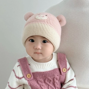Close-up of pink and white baby knit hat with 3D animal ears and cute facial embroidery