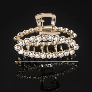 Detail of 5.5cm gold-plated hair claw with shimmering rhinestones on black background