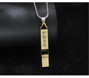 Close-up of vintage bronze whistle pendant with LOVE engraving on a silver chain