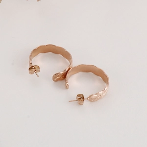 Detailed close-up of C-shaped rose gold earrings with retro geometric texture