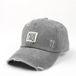 Makro-Detail einer grauen Denim-Cap im Distressed-Look mit MARIA-Stickerei und Löchern