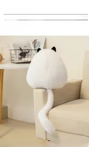 Rear view of white plush Persian cat toy showing rounded shape and long tail on a sofa