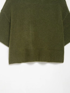Détail du pull en maille vert foncé avec texture pelucheuse et ourlet côtelé
