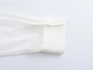 Dettaglio della manica in rete trasparente e del polsino bianco con bottone su camicia