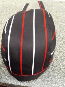 Detailed top view of a black chef hat with red and white stripes on textured stone background